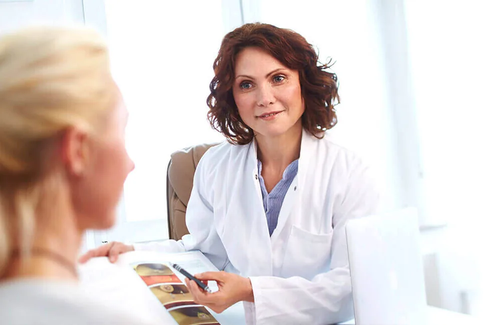 Dr. Feldman im Beratungsgespräch mit einer Patientin am Tisch